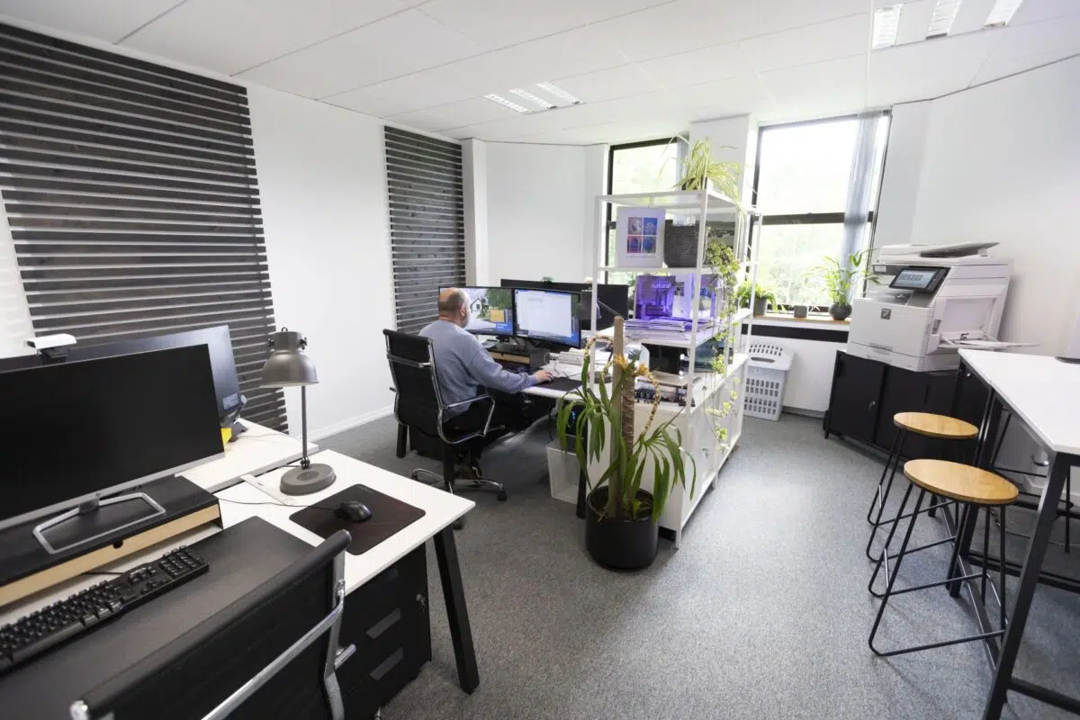 A serviced office at Watermoor Point in Cirencester, with a member working at a multi-monitor desk