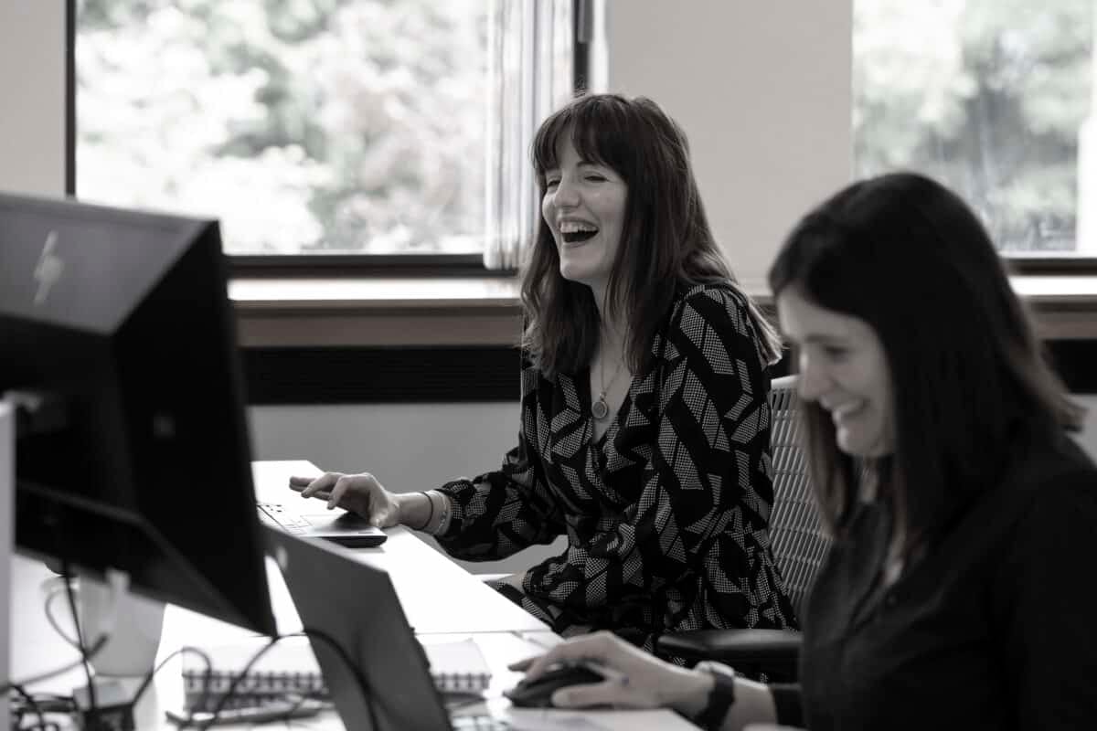 Two colleagues laughing together at a desk
