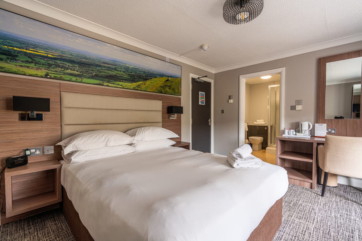 A Riverside hotel room with a bed, desk and seating area
