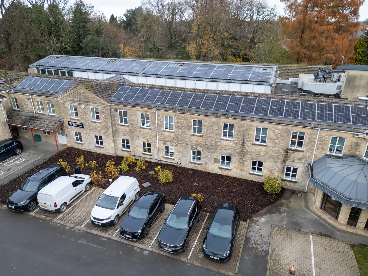 Aerial view of the Trinity Road building in Cirencester, Cotswold stone with rooftop solar panels and parking