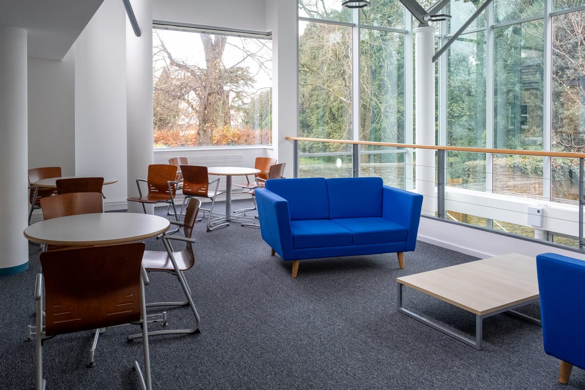 A bright breakout lounge at Trinity Road, looking out over the trees