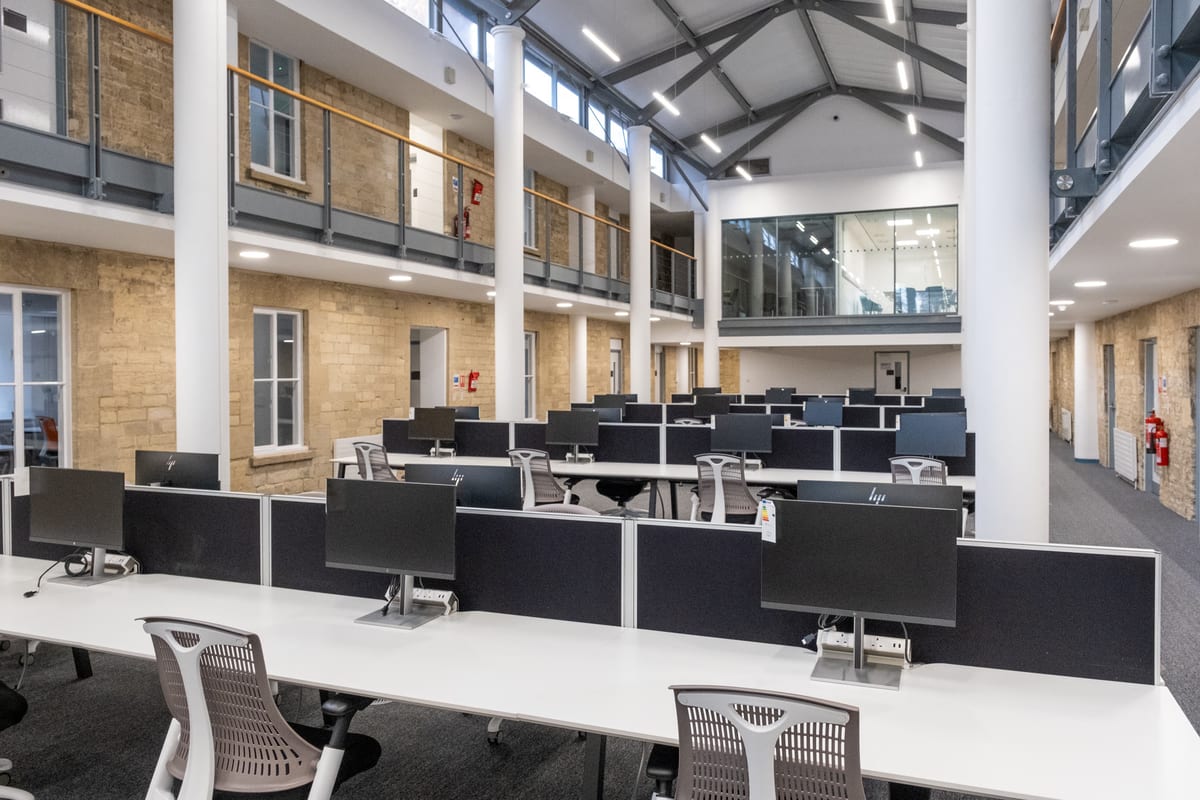 Rows of co-working desks beneath the restored central atrium at Trinity Road