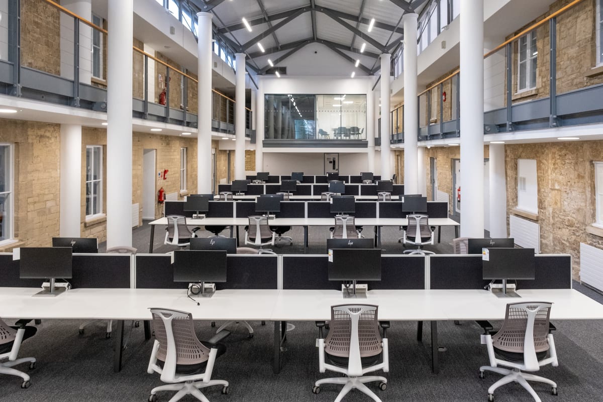 The open-plan co-working hall at Trinity Road, with dedicated desks and HD monitors